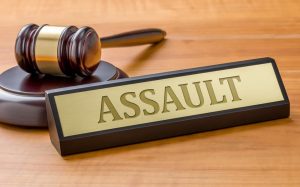 Gavel on desk with tag next to it listing the word assault.