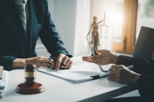Lawyer speaking to client at desk with statue of justice on top of it