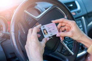 Person holding a driver's license inside a car.