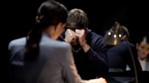 Man with head in hands during an interrogation with a female officer.