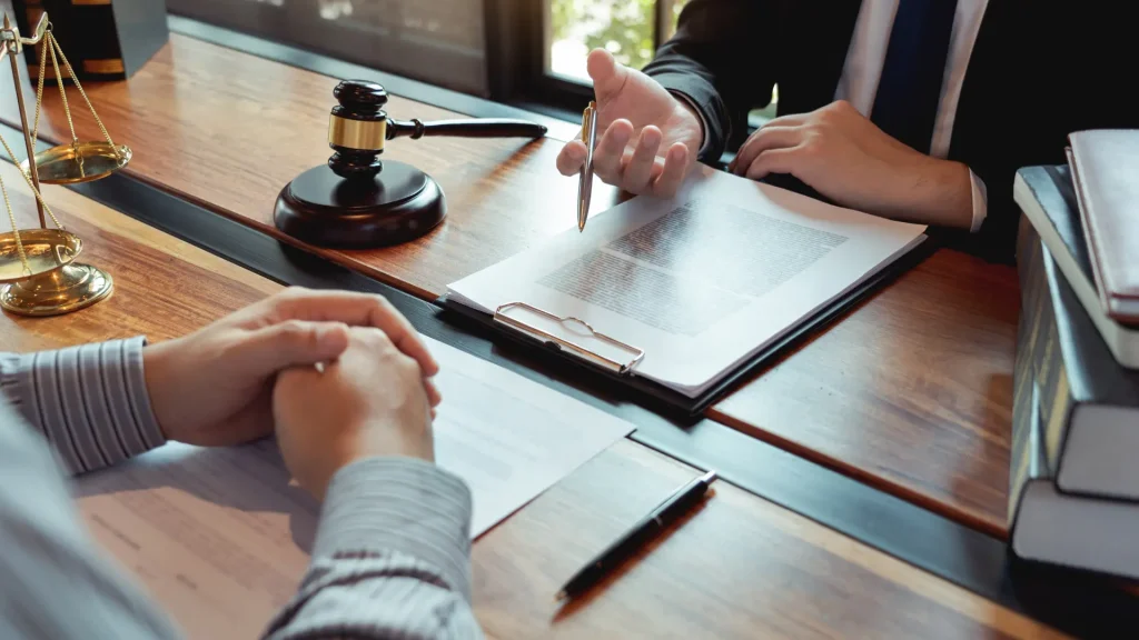 Two people discussing legal documents with a gavel on the table.