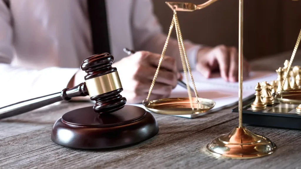 Gavel, scales of justice, and a person writing on documents.